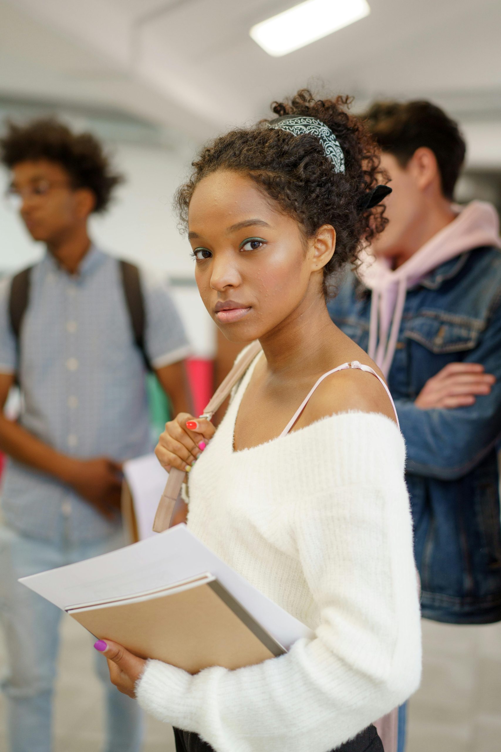 A young woman carries notebooks, embodying focus and determination in a classroom setting.