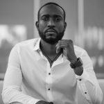 Black and white portrait of a stylish man in a white shirt indoors.
