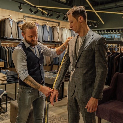 Tailor measuring a customer in a suit store for a perfect fit.