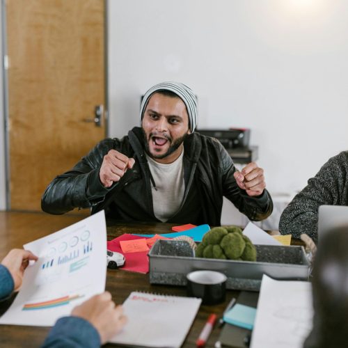 Energetic office meeting showcasing teamwork and innovative idea sharing among young entrepreneurs.